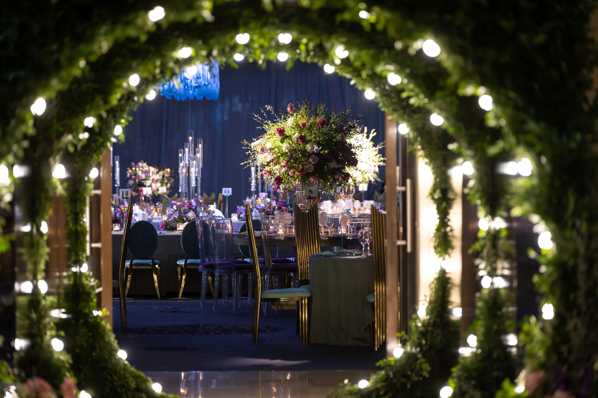 Arco iluminado de follaje con salón de banquete al fondo
