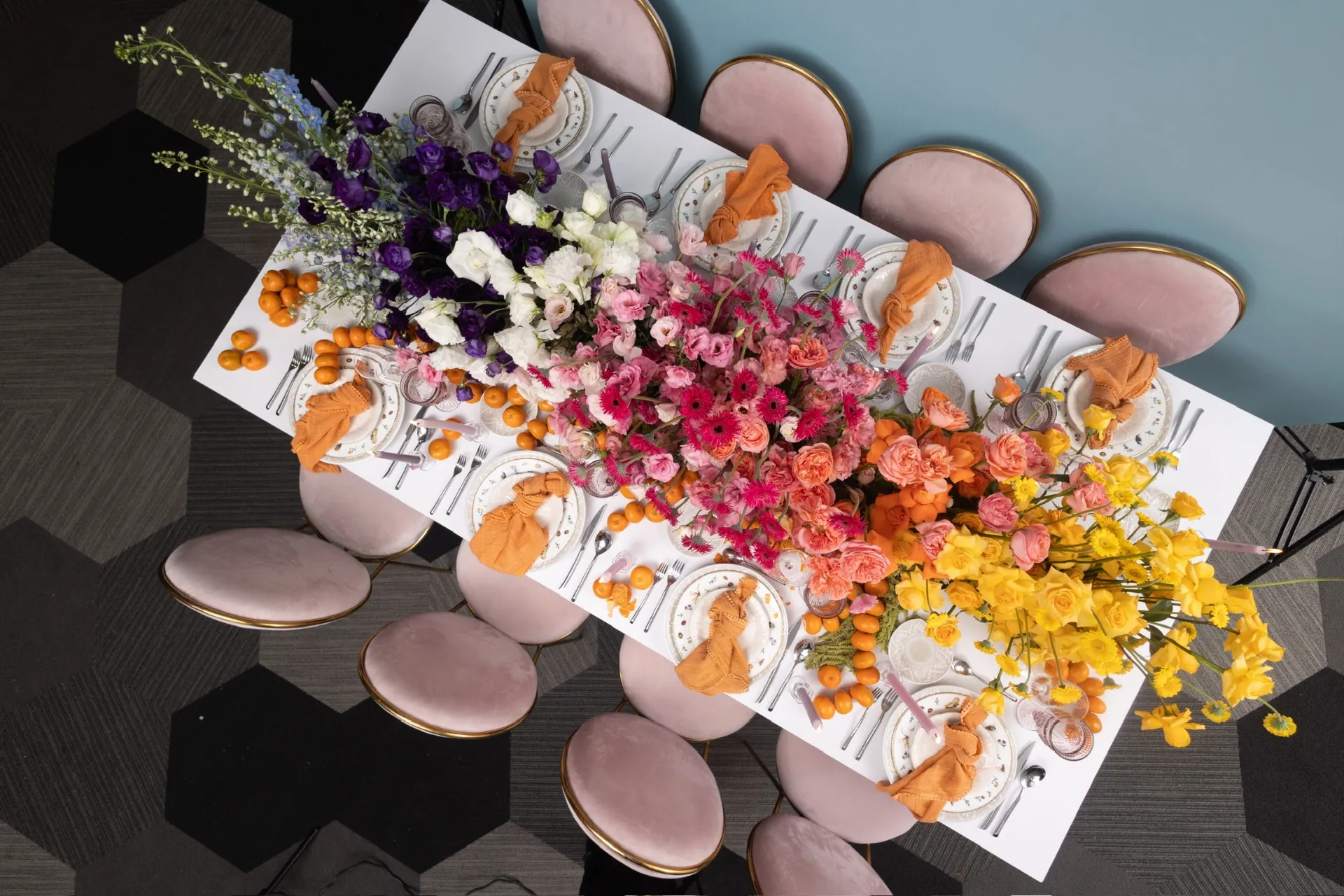 Vista cenital de mesa imperial con flores frutales y sillas rosas