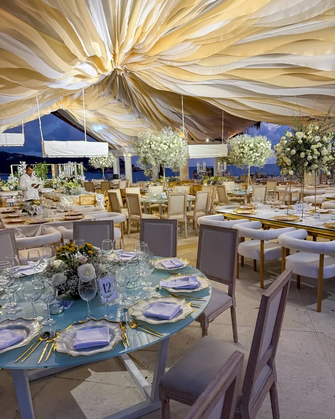 Boda frente al mar con techo de telas y sillas de madera